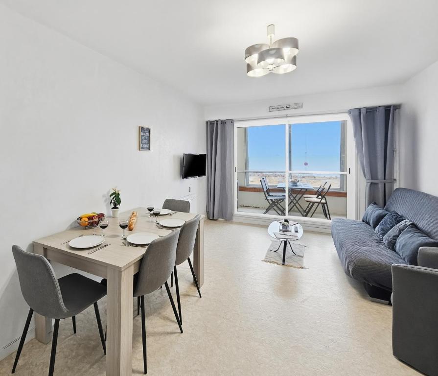 a living room with a table and a blue couch at Sérénité vue mer in Courseulles-sur-Mer