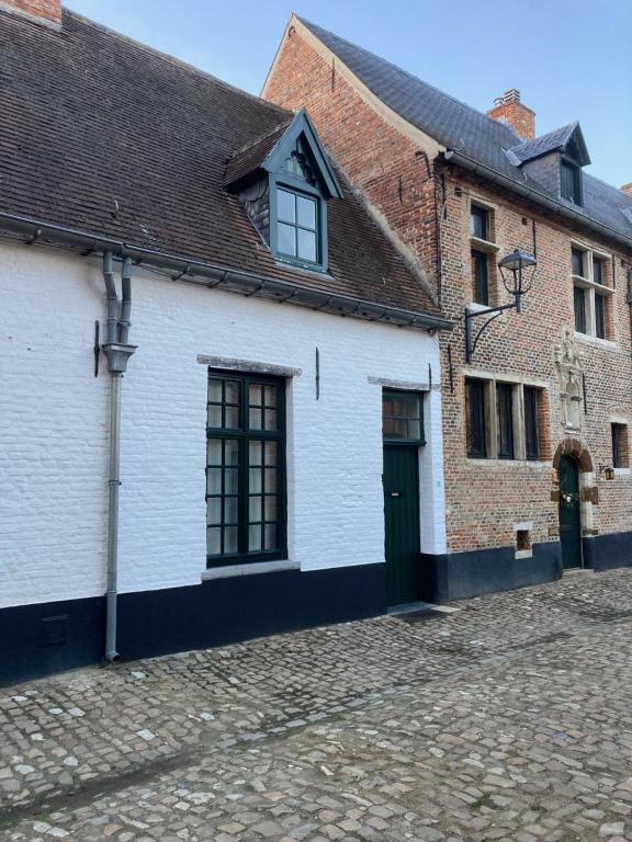 ein weißes Gebäude mit einer grünen Tür an einer Straße in der Unterkunft Maison Konvent in Diest