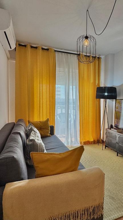 a living room with a couch and yellow curtains at CityLife Torrevieja in Torrevieja