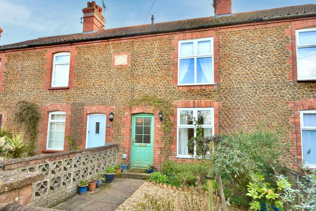 an old brick house with a green door at Carrstone Cottage, Snettisham in Snettisham