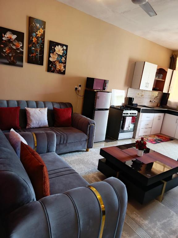 a living room with couches and a table and a kitchen at Catwalk Factory Apartment in Ukunda
