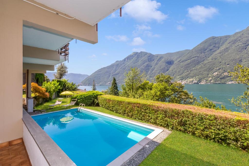 a swimming pool in front of a house with a view of the water at Villa Marilyn in Nesso