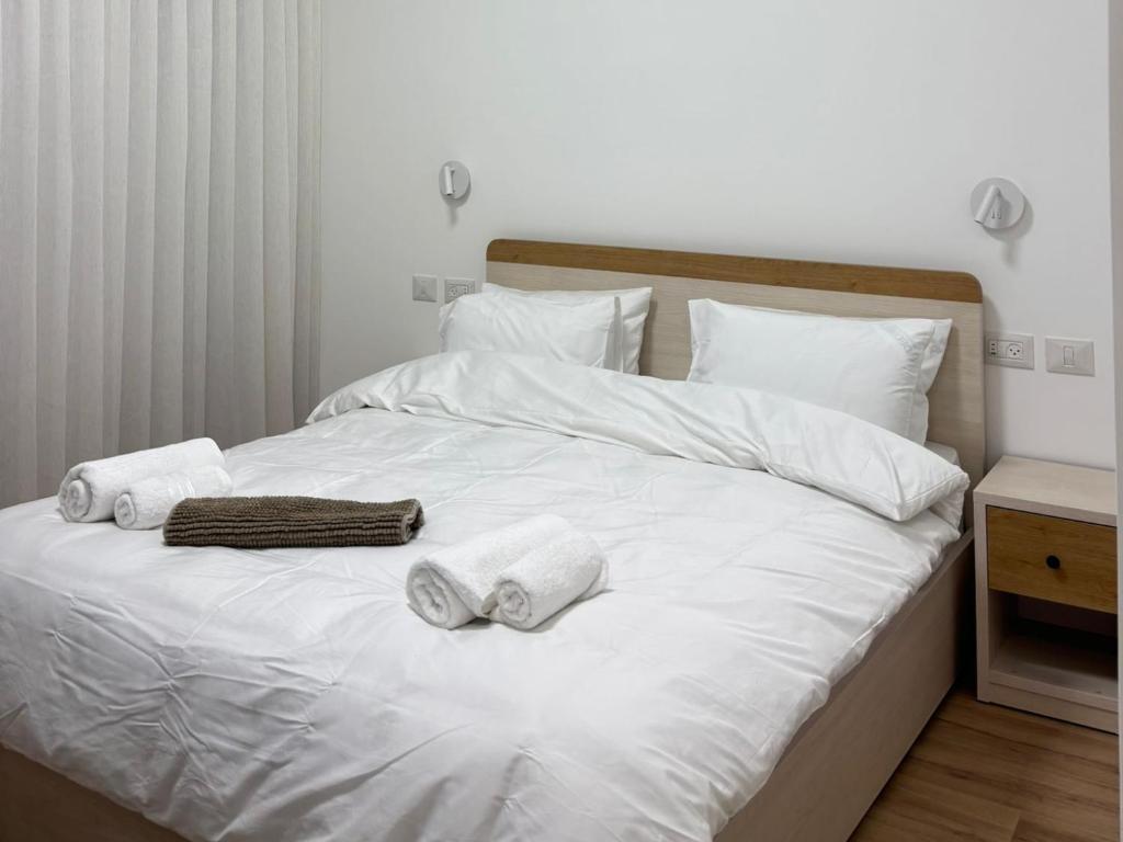 a bed with white sheets and towels on it at Koresh 10 - Emilia suite in Jerusalem