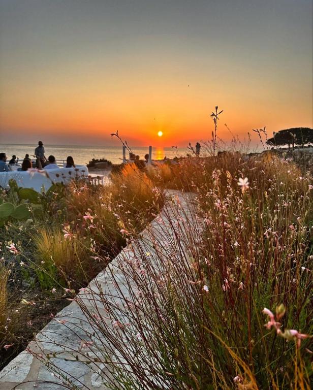 a sunset on the beach with people sitting on the beach at Sunset Studios & Rooms in Antiparos