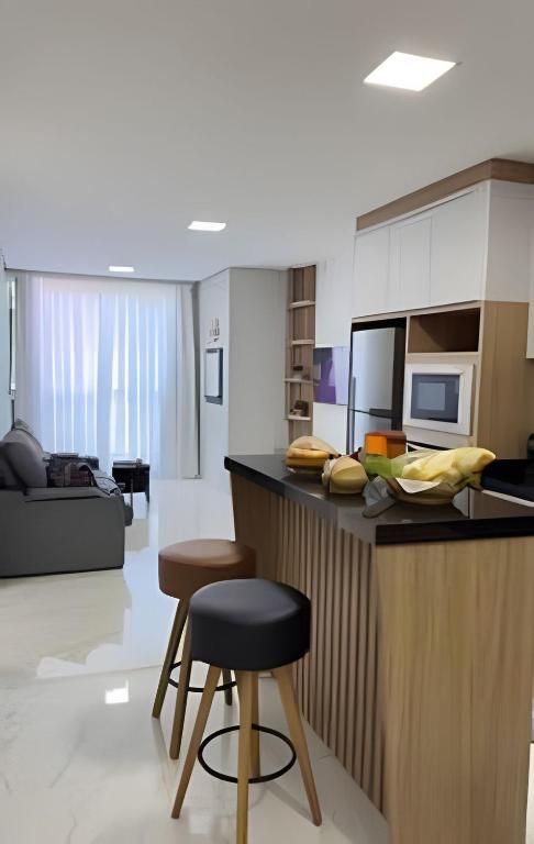 a kitchen with a counter and two stools in a room at Apto Lavandas|2Qts.Lado Centro Eventos,150m Termas in Piratuba
