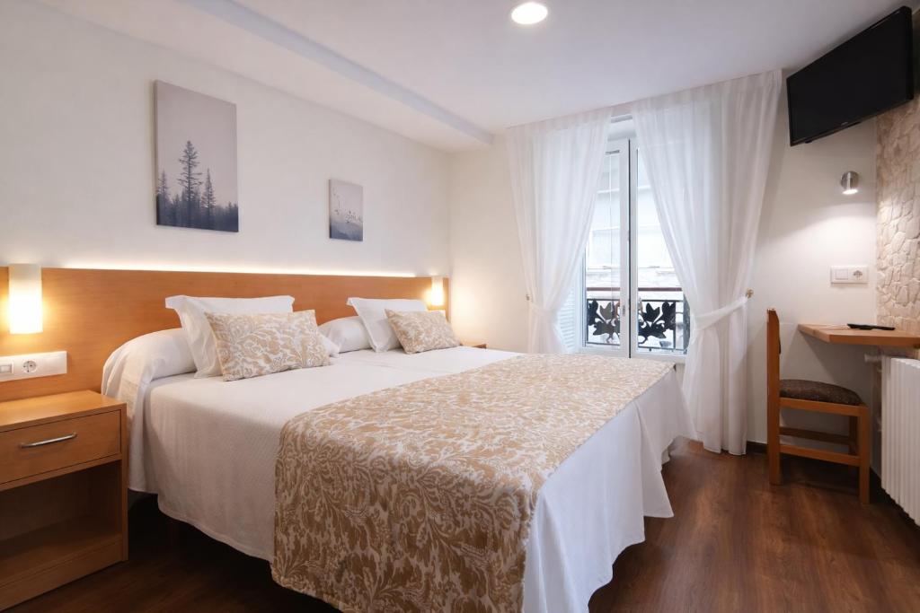 a bedroom with a large white bed and a window at Hostal Anosa Casa in Santiago de Compostela