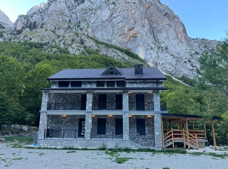 a stone house with a mountain in the background at Guest House Ropojan in Vusanje