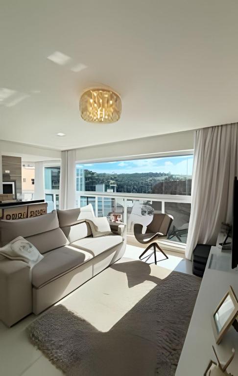 a living room with a couch and a large window at Apto Margaridas|3Q,todo Climatizado,ao lado Termas in Piratuba