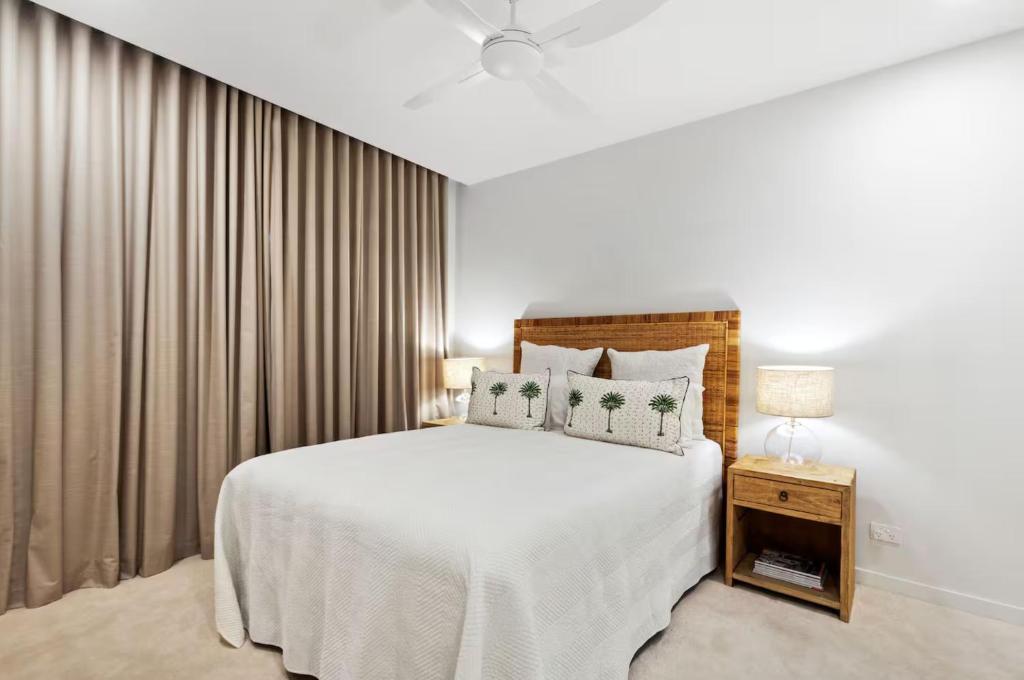 a bedroom with a large white bed and curtains at THE COSMOPOLITAN COTTON TREE Unit 10207 Cotton Tree in Maroochydore