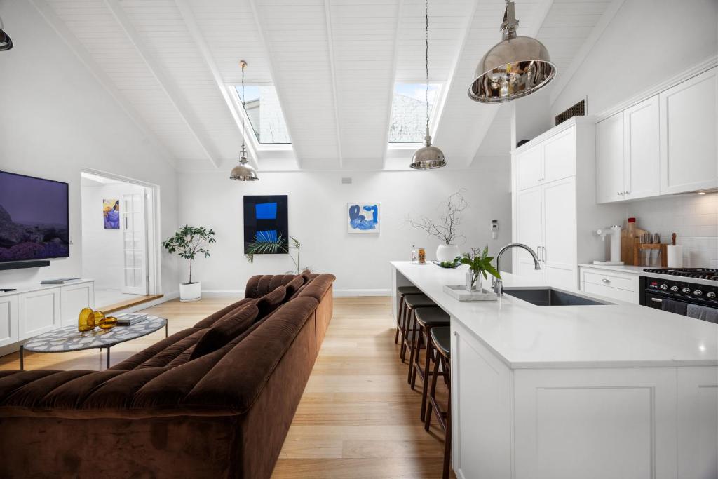 a living room with a couch and a kitchen at Eastside Oasis - Heart of Norwood with Poolside Garden in Norwood