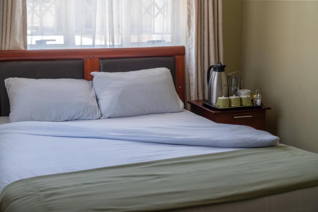 a bed with white sheets and pillows next to a window at Timba Lodge in Blantyre