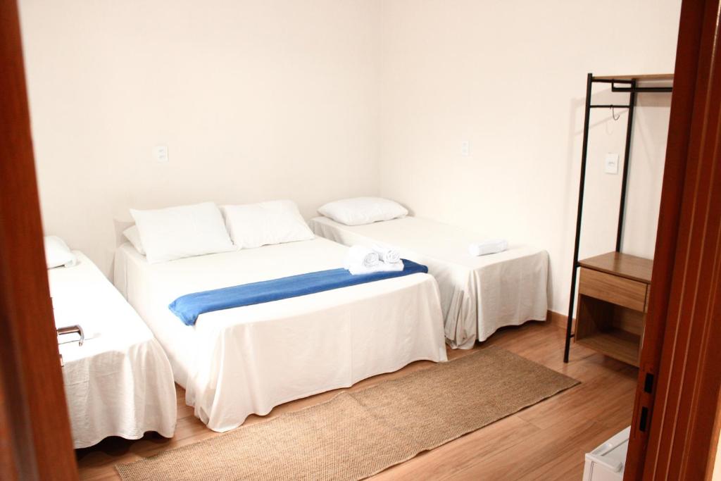 a bedroom with two beds with white sheets and a mirror at Pousada - Árvore da Vida in Bonito