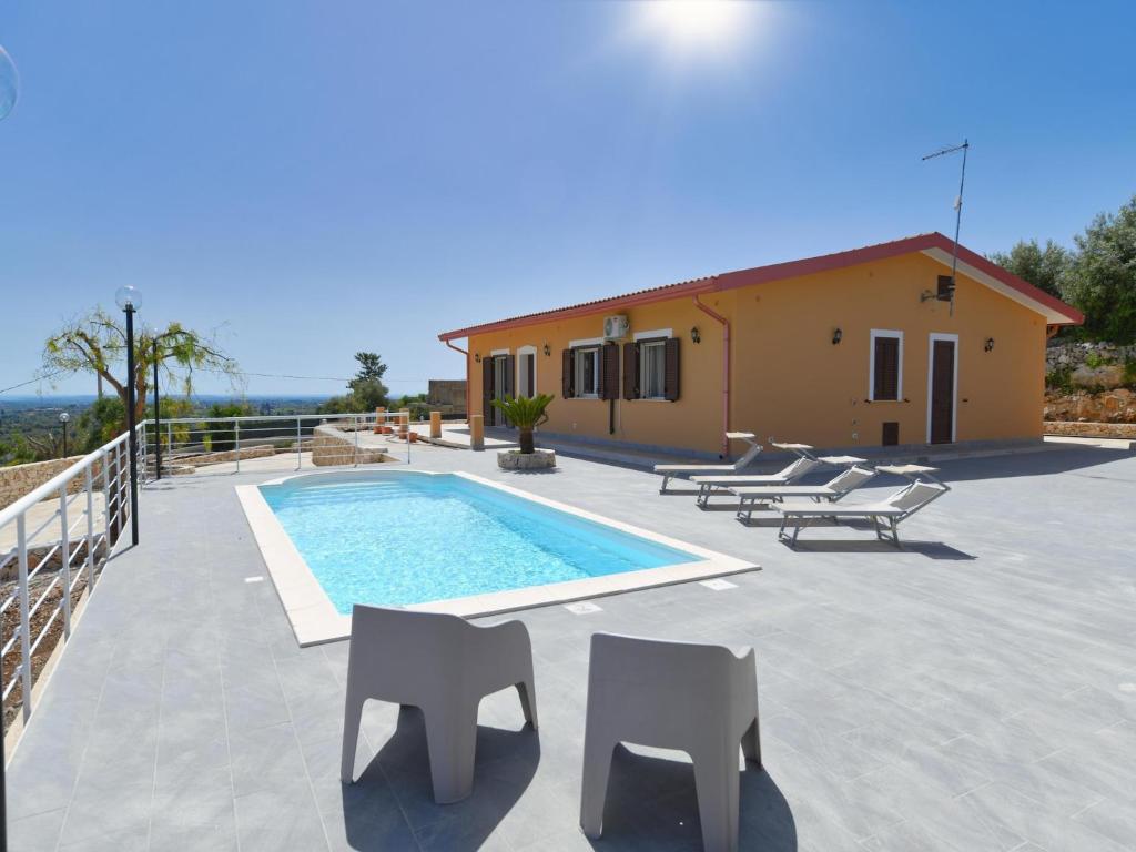 a villa with a swimming pool and chairs and a house at Villa with private pool in Floridia in Floridia