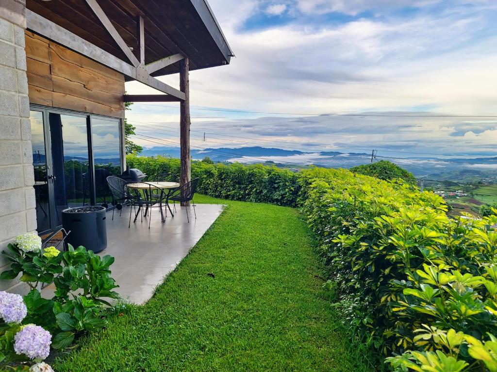 a patio with a table and chairs on the side of a house at Private Mountain Cabin with Garden Views in Zarcero
