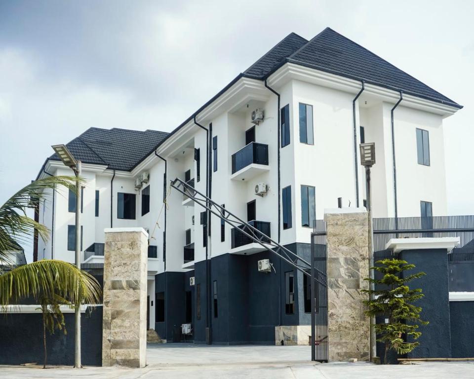 a large white building with a black garage at Rex&Rich Hotel and Suites in Umu Oma