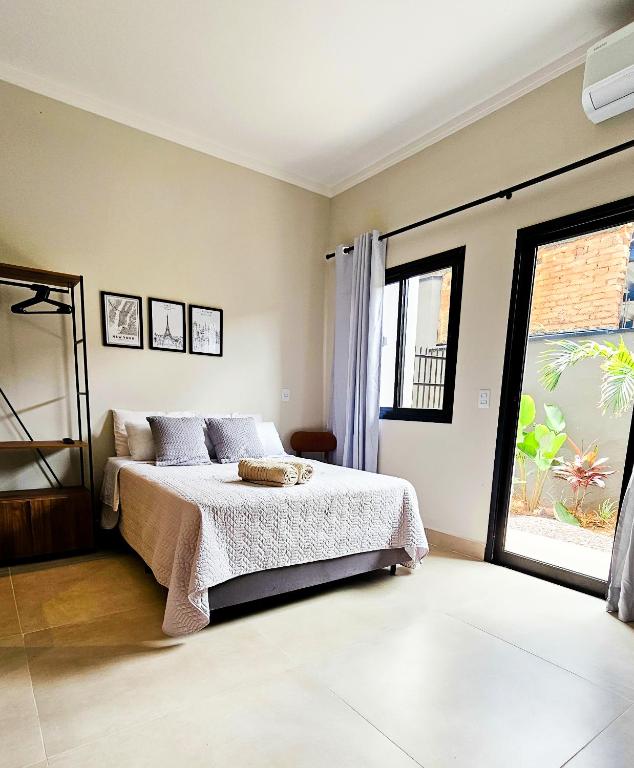 a bedroom with a bed and a large window at Studio moderno no centro de vinhedo in Vinhedo