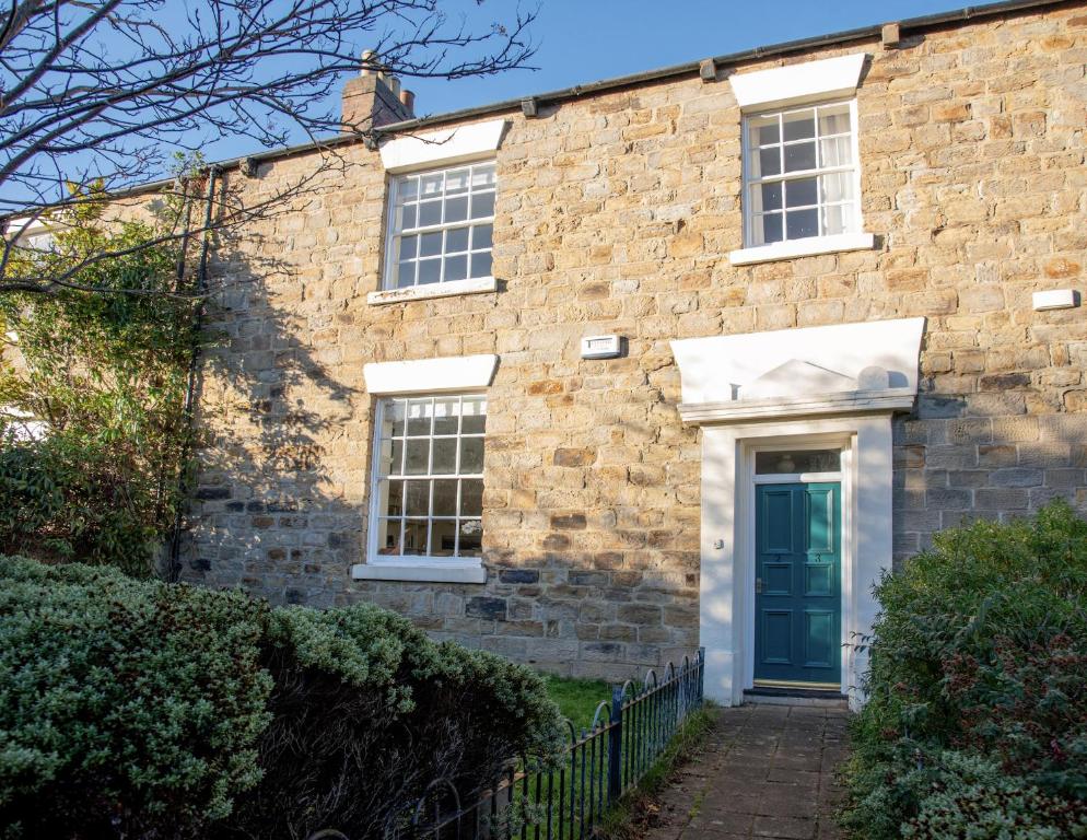 a brick house with a blue door and windows at St Margarets Mews in Durham