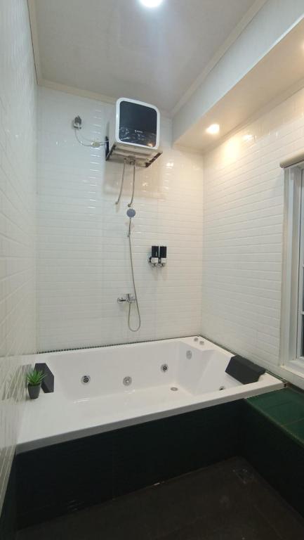 a bathroom with a bath tub with a tv on the wall at Sukabumi Villa Mochi Private Jacuzzi in Sukabumi
