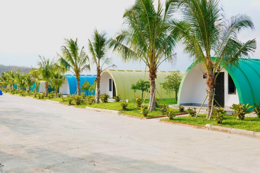 a row of houses with palm trees on the side of a road at Kakse Teschor Mong Reththy Senchey in Phumĭ Svay Dângkum