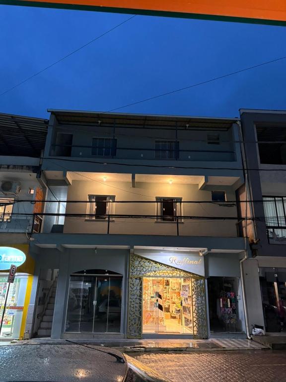 a white building with a balcony on a street at Doce Lar Alto Caparaó in Caparaó Velho
