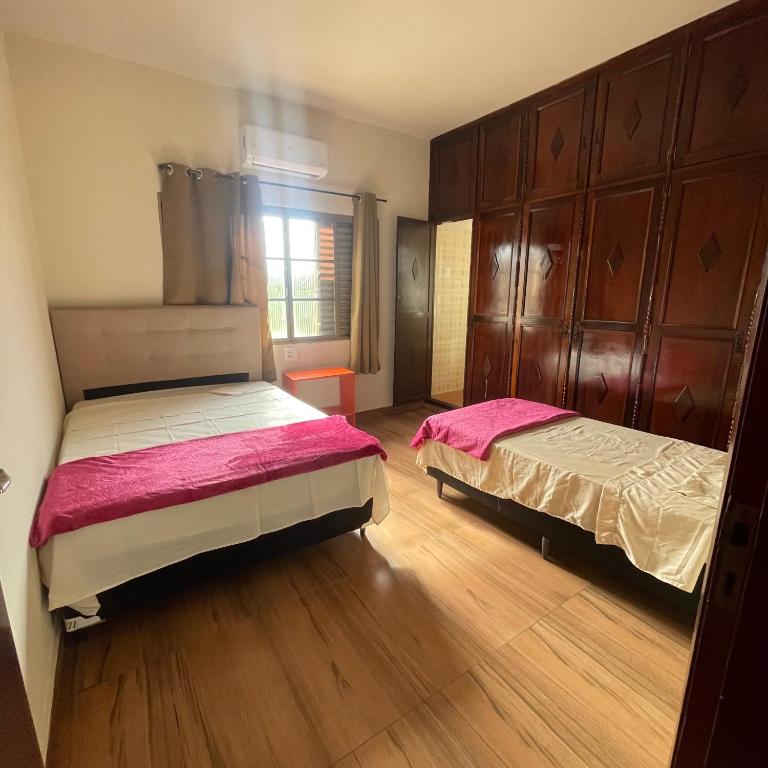 two beds in a room with wooden floors at Morada 1000 - Pousada in Frutal