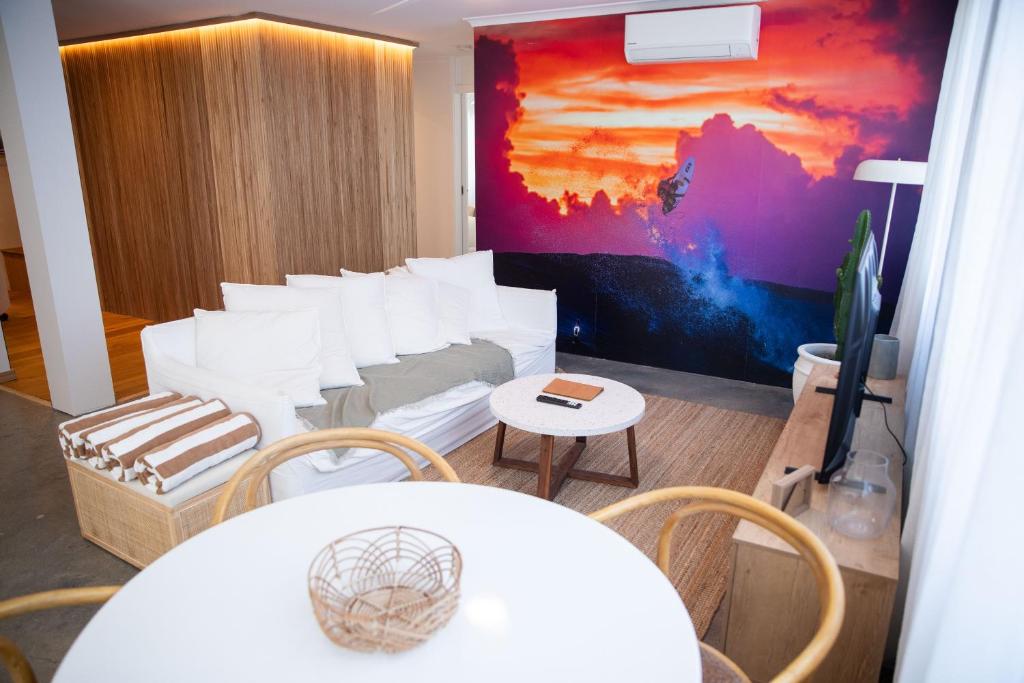 a room with white chairs and a couch and a painting at El Parche Bilinga Beachside in Gold Coast