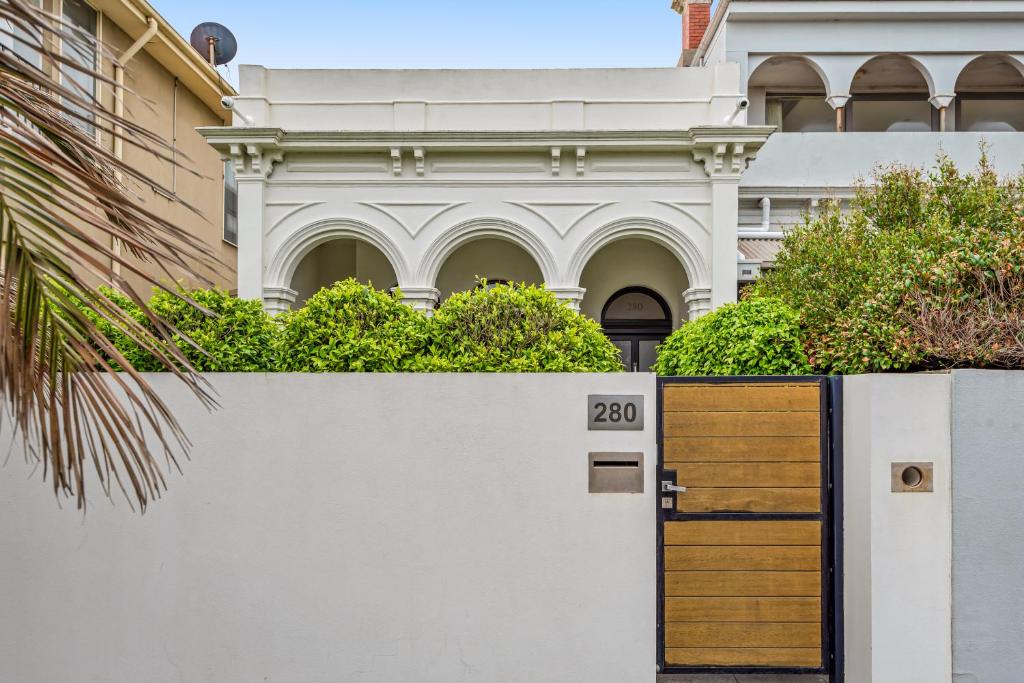 a white fence with a wooden door in front of a building at Complete Host Middle Park House in Melbourne
