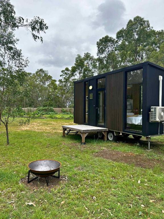 a black tiny house with a bench and a table at Mirror Reflections 2 by Tiny Away in Tamborine