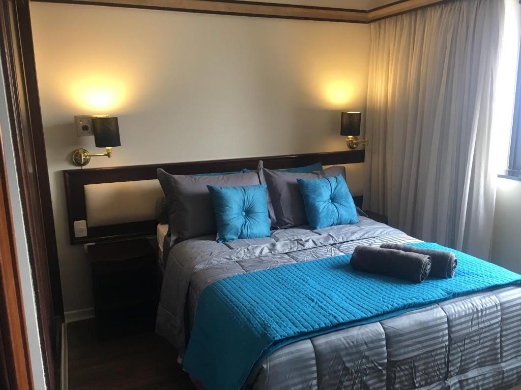 1 dormitorio con 1 cama grande con almohadas azules en Apartamento confortável - Jd Paulista, en São Paulo