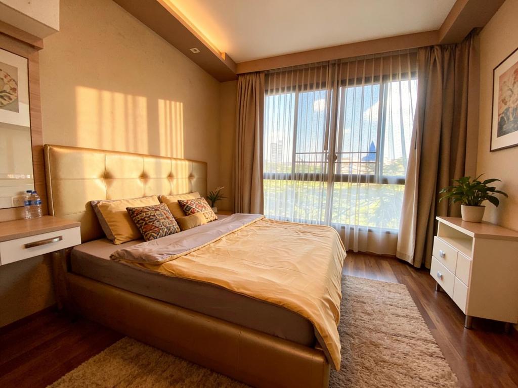 a bedroom with a large bed with a large window at Treasure Condo Kitchenette Wifi in Chiang Mai
