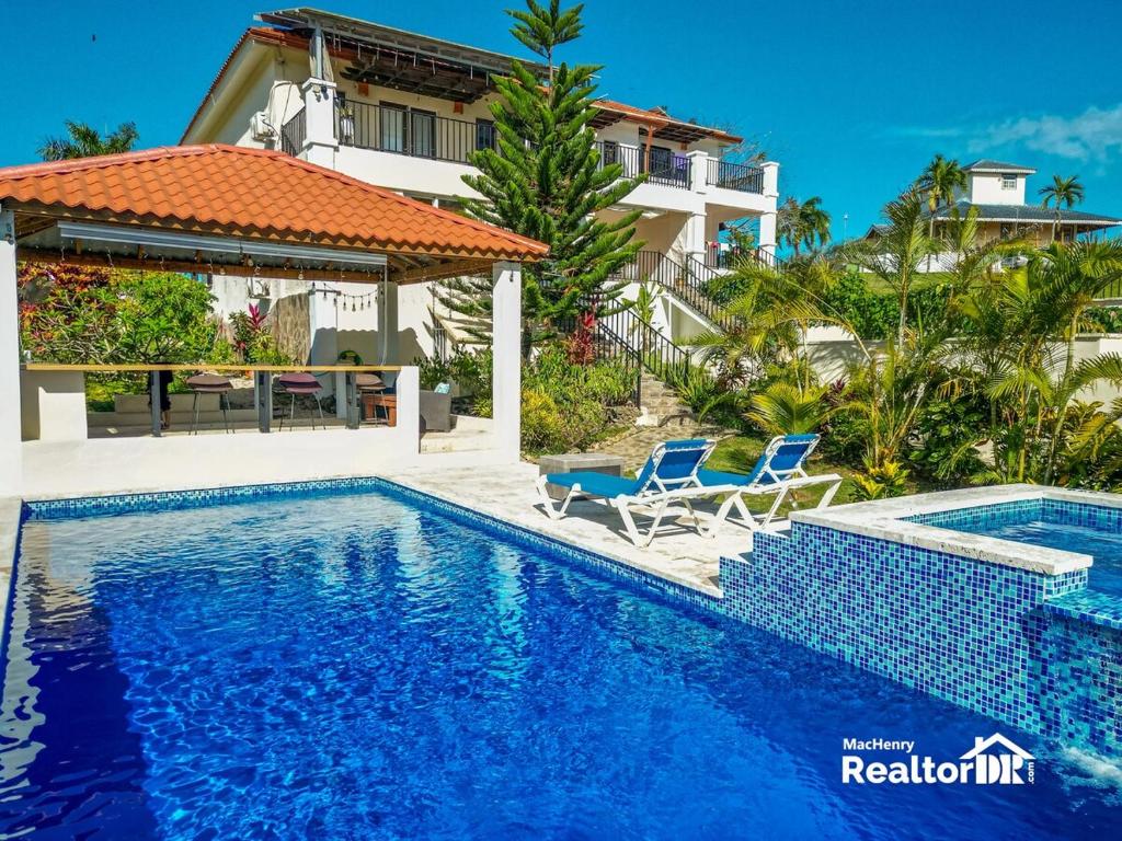 a swimming pool with two chairs and a house at Casa Estrella, Relaxation Begins in Sosúa