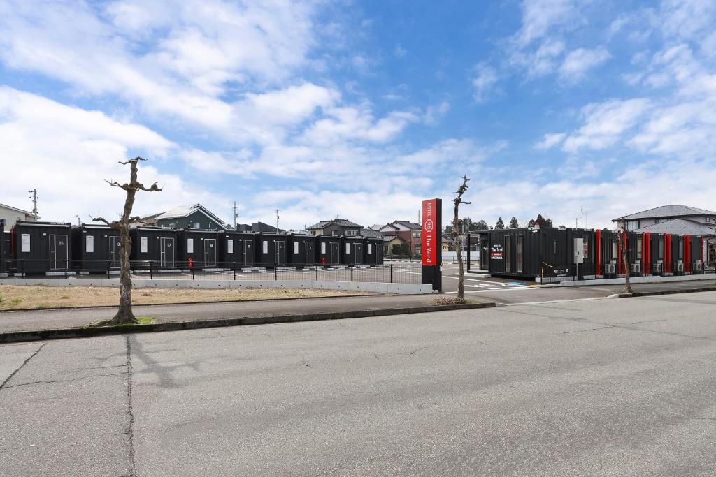 an empty street with a building with a red sign at HOTEL R9 The Yard Namerikawa in Namerikawa