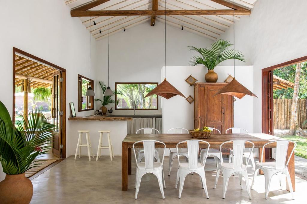 a dining room with a wooden table and white chairs at Casa Pini - Condomínio Altos de Trancoso, próxima ao Quadrado in Trancoso