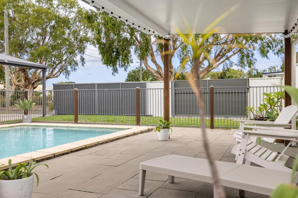 a backyard with a swimming pool and a white fence at Pet Friendly Beachside Hideaway - Lazy on Lowry in Woorim