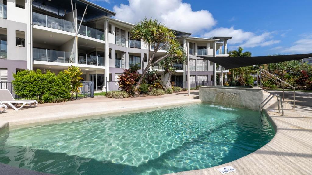 a swimming pool in front of a building at Waterline Direct Poolside Apartment in Agnes Water