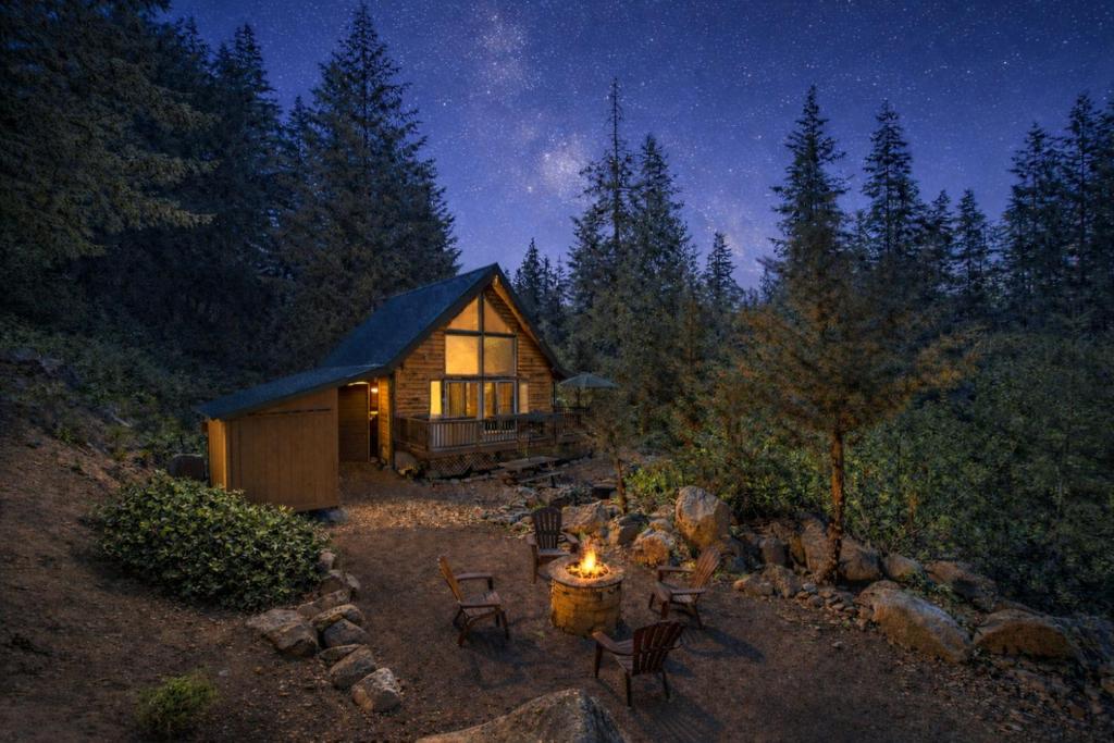 a cabin in the woods at night with a fire sidx sidx sidx sidx at Raven Haven Lodge by NW Comfy Cabins in Leavenworth