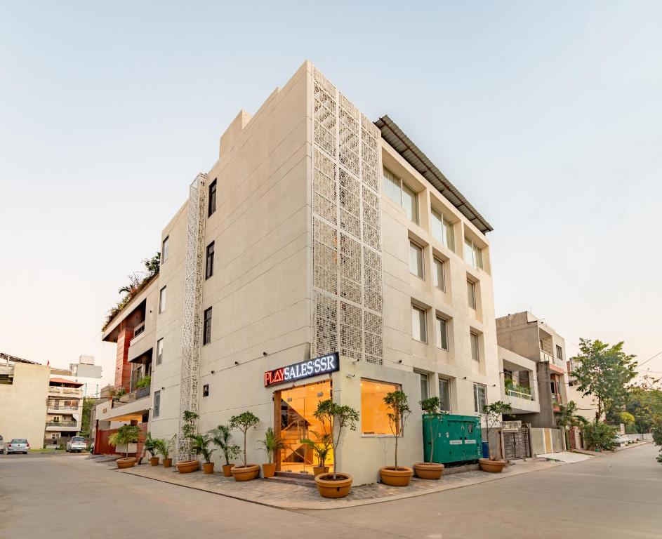 a tall white building with potted plants in front of it at Playsales SSR in Indore