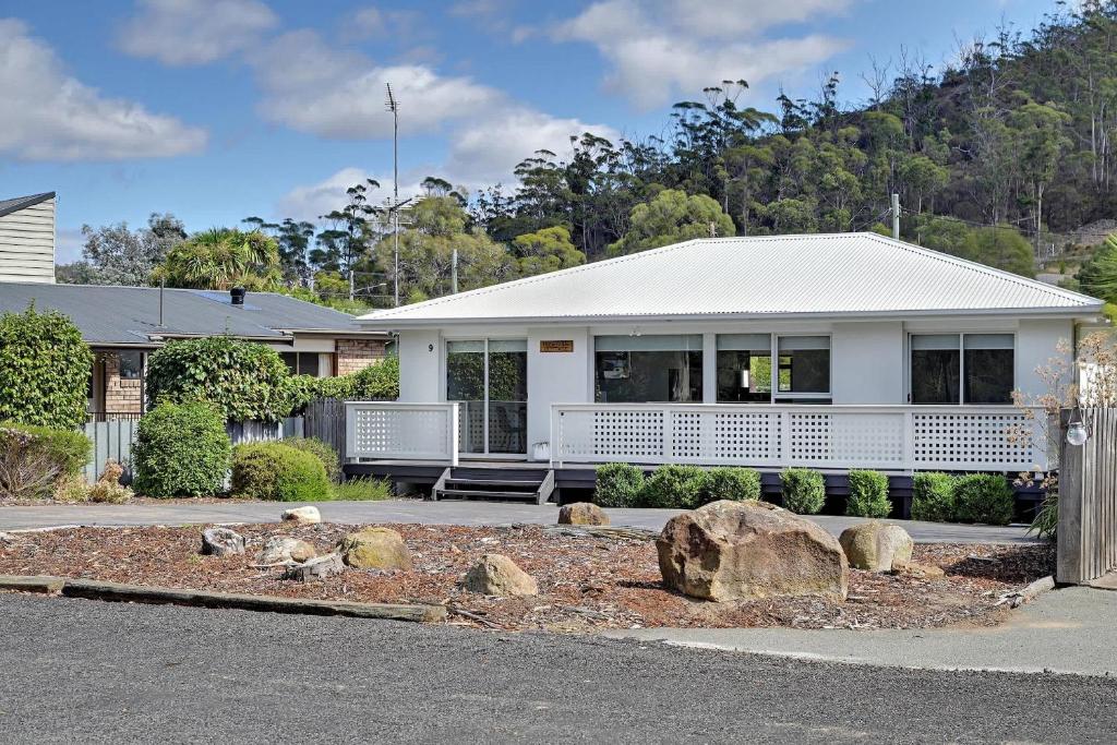 a white house with a porch and a yard at Orford Waterfront Cottage in Orford
