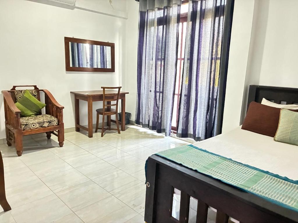 a bedroom with a bed and a table and a chair at Amani Rooms in Panadura