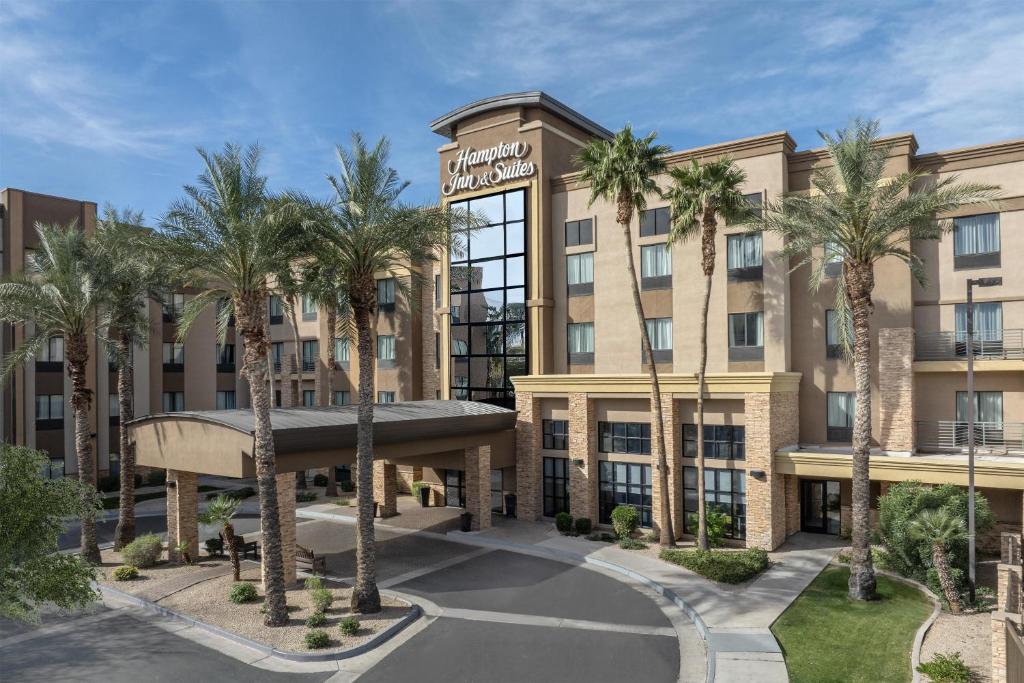 an image of the front of a hotel with palm trees at Hampton Inn & Suites Phoenix Glendale-Westgate in Glendale