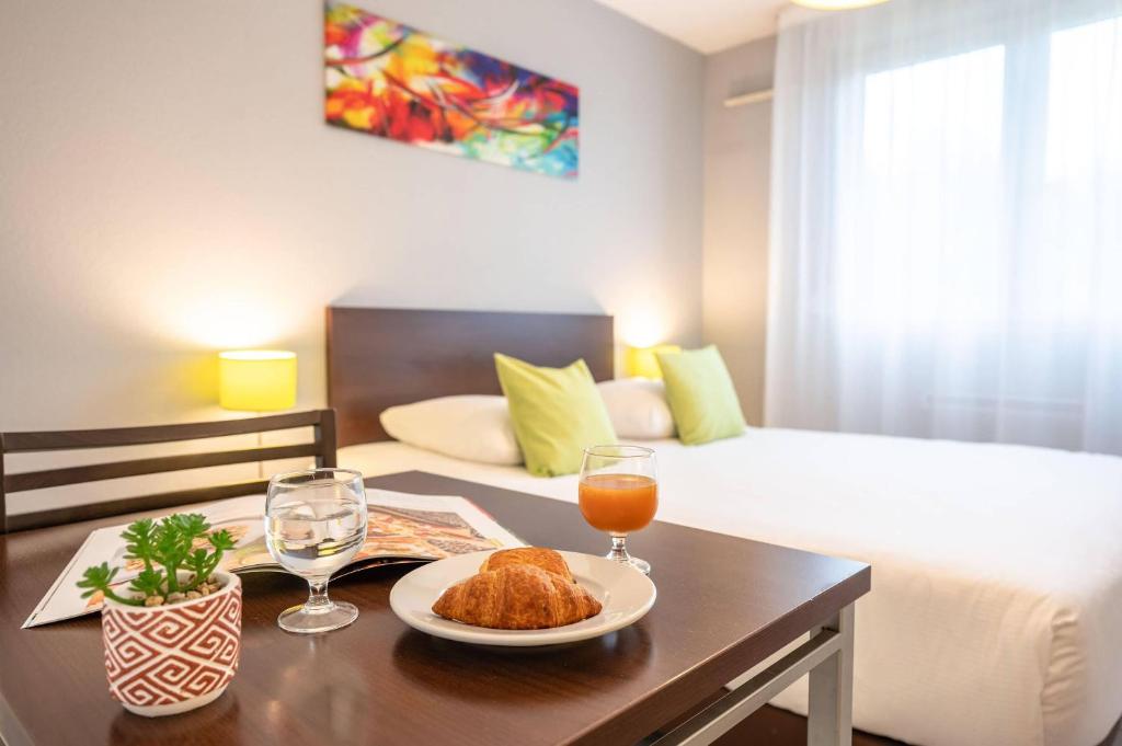 a room with a bed and a table with a plate of food at Comfort Aparthotel Besancon La City in Besançon