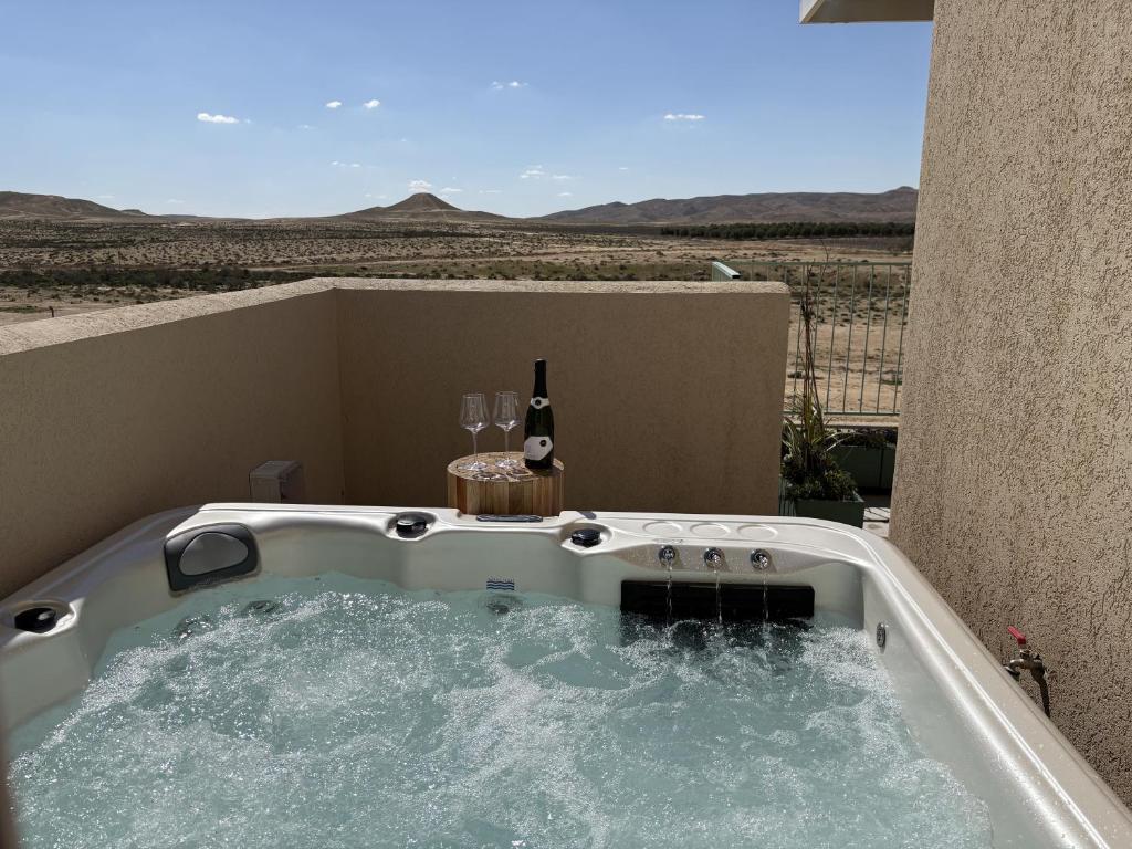 a hot tub with a bottle of wine and two glasses at בקצה הוואדי - The Wadi Edge in Yeroẖam