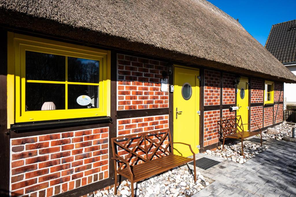 a small brick building with yellow doors and a thatched roof at Alte Scheune Koserow bei Baltic Home in Koserow