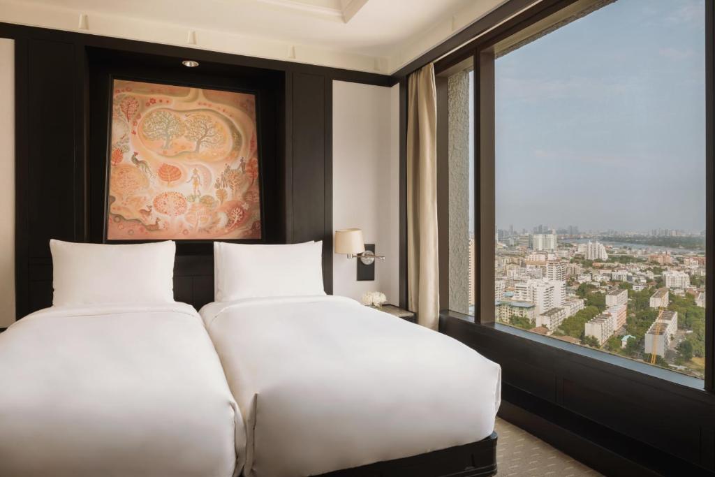 A twin-bedded room with expansive windows over the city.