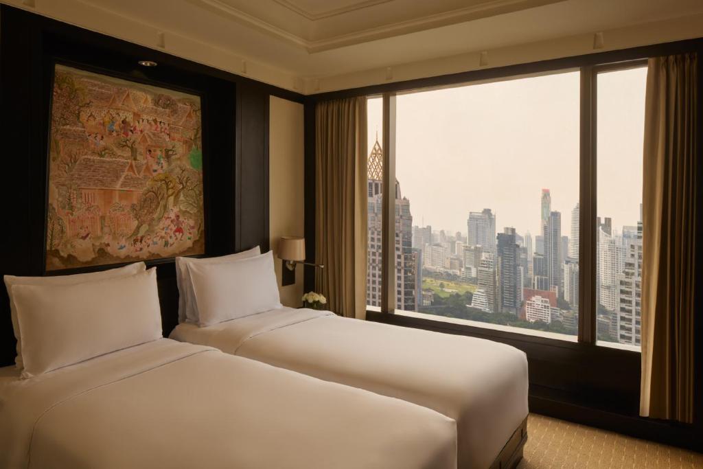 A twin-bedded room with a panoramic high-rise skyline through the main window.