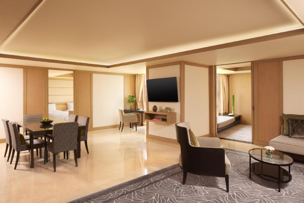 A large living room with a dining table, television, lounge chair and adjoining bedroom views.