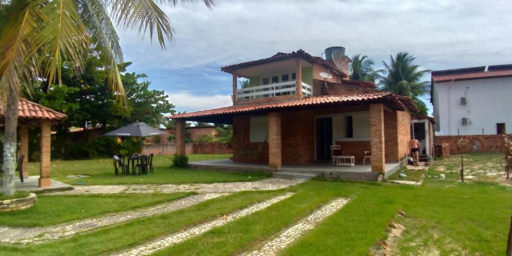 a house with a green yard in front of it at Recanto do Pontal in Japaratinga