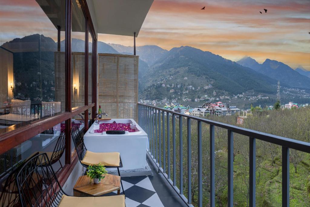 a bath tub on a balcony with a view of mountains at Echor Himalayan Aurum Resort & Spa, Manali in Manāli