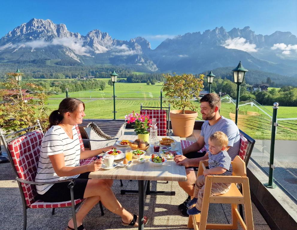 a family sitting at a table eating food at Hotel Ritterhof Ellmau in Ellmau