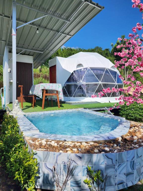a swimming pool in a yard with a tent at Phunapat camping Dome in Ban Song Phi Nong